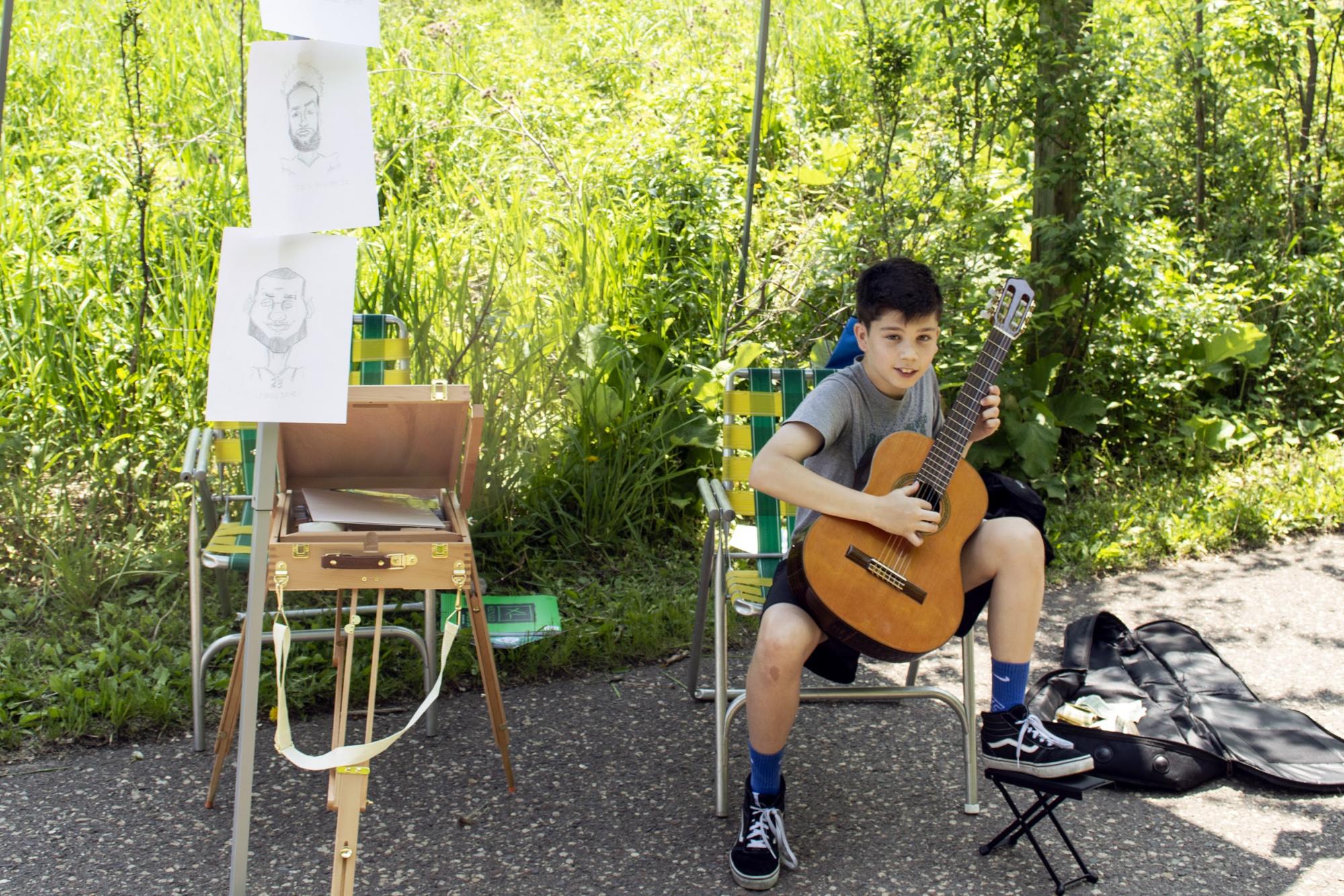 Henry Colin, an 11-year-old artist and musician, plays guitar at Art in the Hollow. Colin also drew caricatures at this year’s event. (Mandy Hathaway / The Metropolitan)