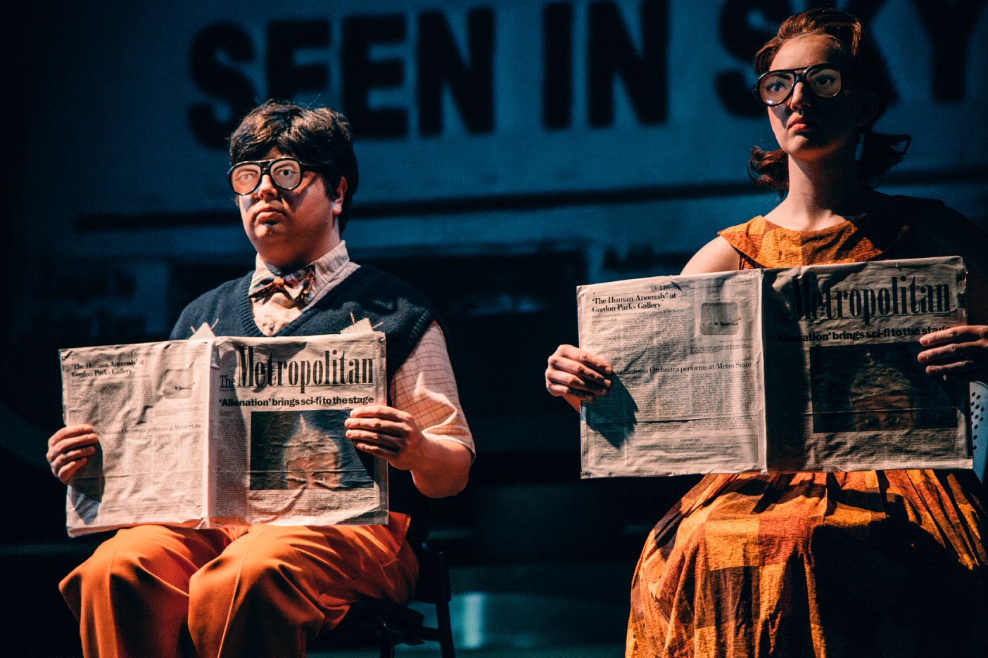 Maurice Manton, left, and Anna Pladson read copies of The Metropolitan in a scene from “Alienation,” a winter 2018 production of Metro State’s theater department. (Photo by Matt Benyo)