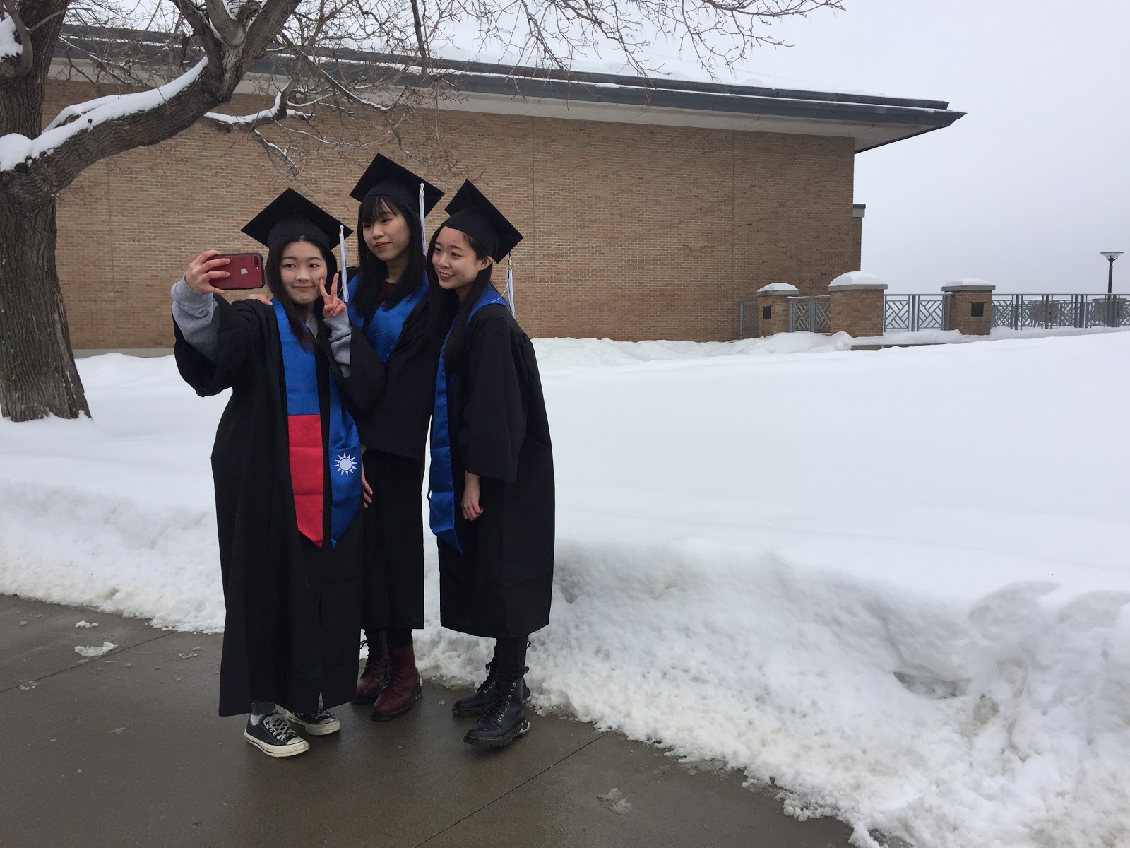 Ya-Hsin Hsueh, left, Chin-Yu Yu and Huei-Cin Chen take selfies in their caps and gowns outside New Main on the St. Paul campus on Saturday, Feb. 23, 2019. The three business administration majors graduate at the end of spring semester and will walk in the commencement exercises at the Minneapolis Convention Center on April 27. They attended the Grad Expo in the Great Hall to purchase their regalia.   (Photo by Margot M. Barry / The Metropolitan)