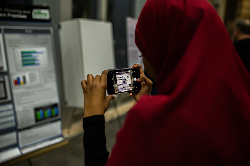 A conference attendee captures an image of a nursing student’s poster. 
Photo by Eli Bartz