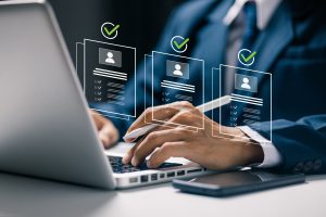 Person reviewing job candidate profiles on a laptop with digital check marks